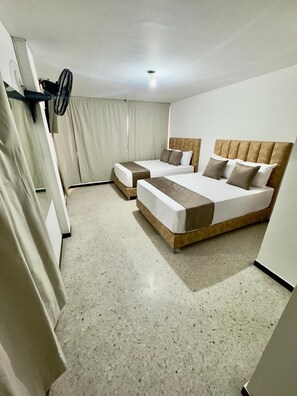 Une chambre d’hôtel avec deux lits, un ventilateur de plafond et un luminaire.