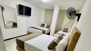 Una camera d'albergo moderna con un letto grande, una televisione a schermo piatto, una ventola a soffitto e uno specchio.