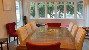 A dining room with a long table, red and yellow chairs, and a hanging light fixture. - Charming B&B steps to beach, boardwalk, pier, shop, restaurants w bath & WiFi #6 (Santa Cruz)