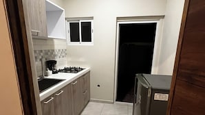 Eine kleine Küche mit einem Gasherd, einer Kaffeemaschine und einem Kühlschrank.