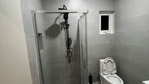 Ein Badezimmer mit Duschkabine, Toilette und kleinem Fenster.