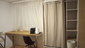 A small room with a desk, chair, and a shelf unit.