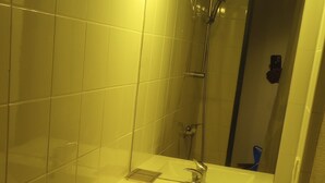 A bathroom with a sink, mirror, and shower.
