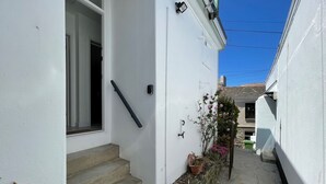 Un sendero estrecho que lleva a un edificio blanco con una puerta y escalones.