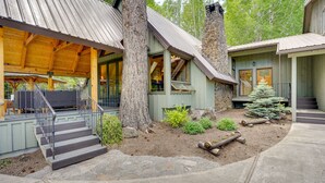 Een landelijke chalet met een overdekte veranda, een trap naar de hoofdingang en een kleine kerstboom in de voortuin.