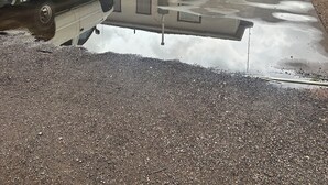 Une allée menant à une résidence, avec un camionnette blanche garée sur le côté gauche.