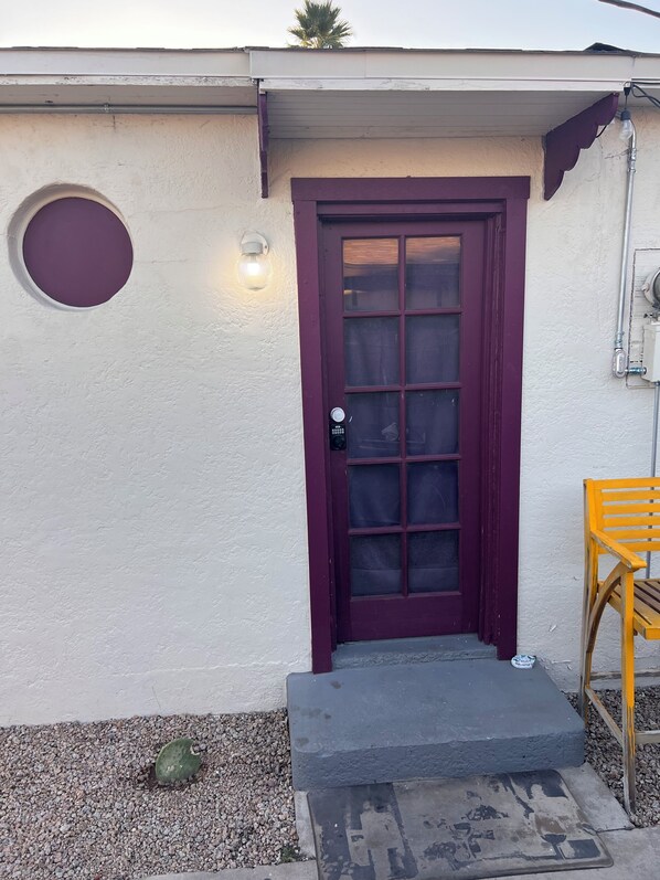A house with a purple door, a light fixture above it, and a small step leading to the entrance.