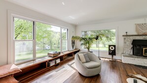 A modern living room with large windows, a fireplace, a built-in bench, and a cozy seating area. - Exclusive 100-Acre Modern Estate Designed Home (Alton)