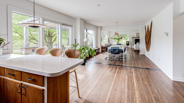 A spacious kitchen with a large island, wooden cabinets, and ample natural light from large windows. - Exclusive 100-Acre Modern Estate Designed Home (Alton)