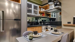 Eine moderne Küche mit einem Edelstahlkühlschrank, Holzschränken und einem Essbereich mit gedecktem Tisch für zwei Personen.