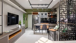 Eine moderne Küche mit Kochinsel, einem Essbereich mit Stühlen und einem an der Wand befestigten Fernseher.