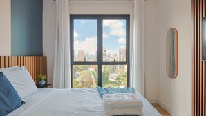 A bedroom with a bed, a view of the city, a nightstand, a potted plant, and a mirror. - Oásis Urbano com Vistas Deslumbrantes no Sky CWB (Curitiba)