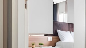 A modern hotel room with a bed, bedside table, and a small plant. - 2 Quartos com Garagem vista incrível no Batel 27a (Curitiba)