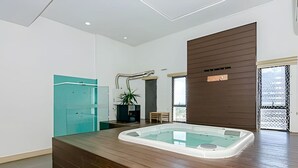 A modern bathroom with a wooden vanity, a glass bathtub, and a potted plant. - Studio incrível no condomínio clube sky Batel soho (Curitiba)