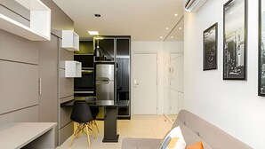 Un espacio habitable moderno y funcional con kitchenette, comedor y sofá con cojines.