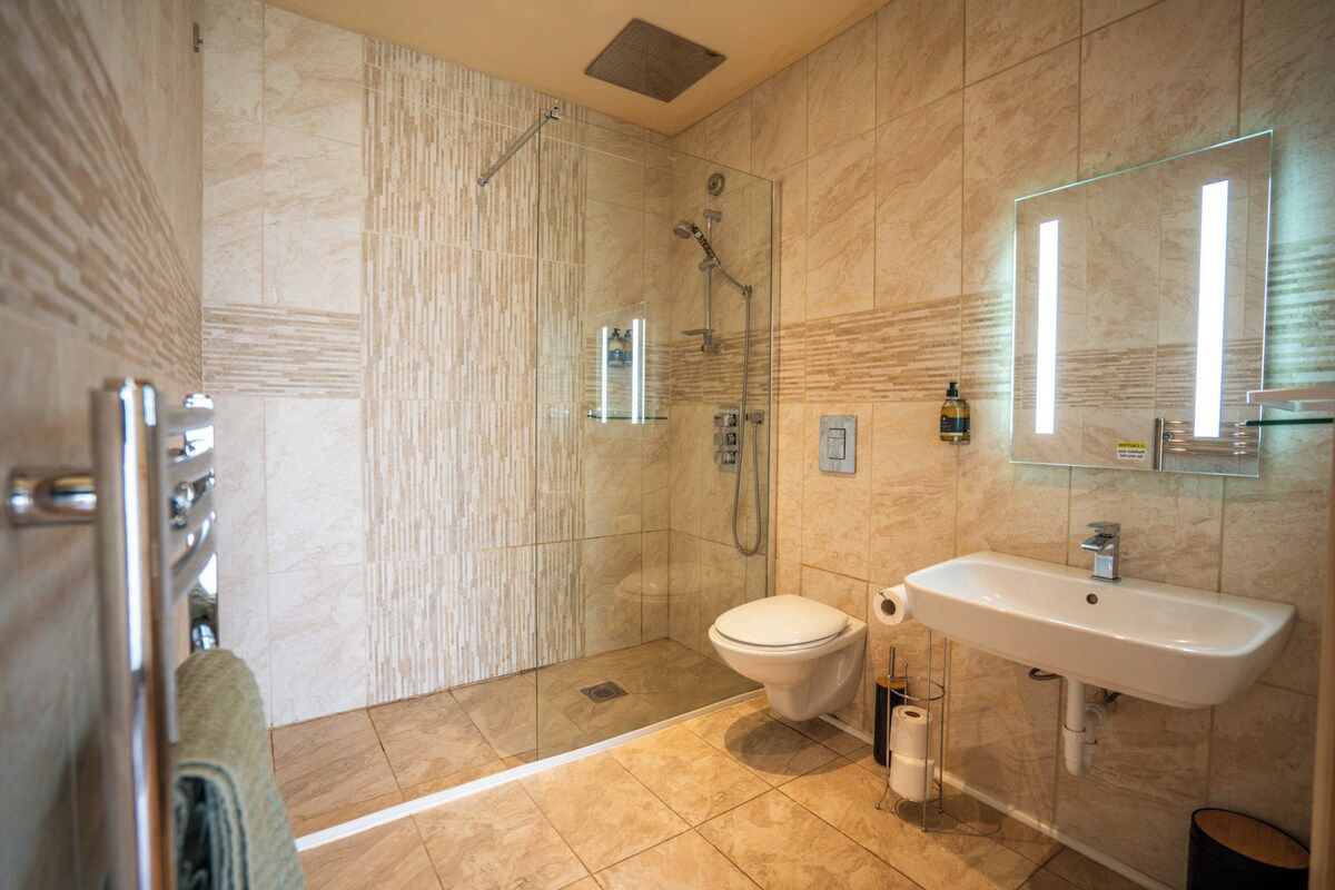 Un baño moderno con ducha acristalada, inodoro blanco y lavamanos con espejo.