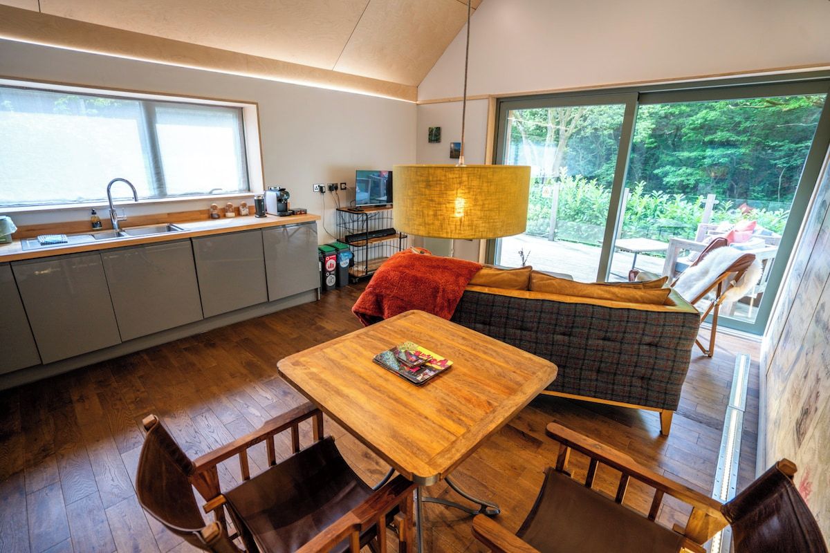 A modern kitchen with a dining area, large windows, and a cozy seating arrangement.