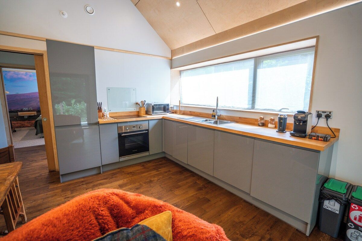 Een moderne keuken met een groot raam, een magnetron, een spoelbak en een fornuis.
