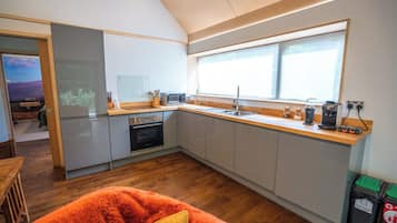 Een moderne keuken met een groot raam, een magnetron, een spoelbak en een fornuis.