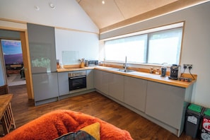 A modern kitchen with a large window, a microwave, a sink, and a stove.