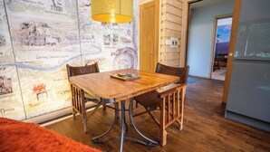 Een eetgedeelte met een houten tafel en stoelen, een wand met een kaart en een deur naar een andere kamer.