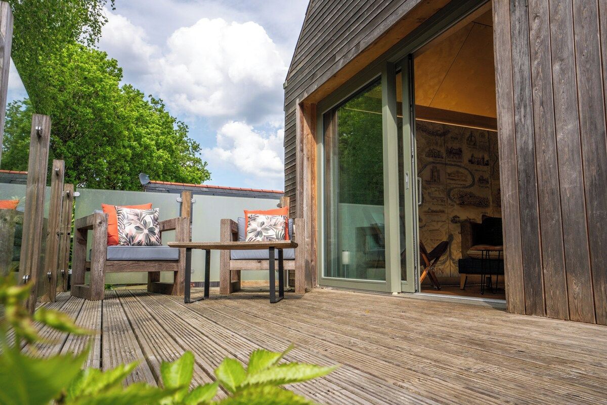 An outdoor wooden deck with a seating area and a sliding glass door leading to a room.