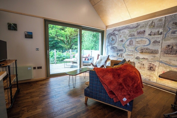 A room with a large sliding glass door leading to an outdoor area, a sofa with a red blanket, and a wall with illustrated landmarks.
