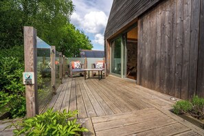 A wooden deck with outdoor seating and a glass door leading to a building.