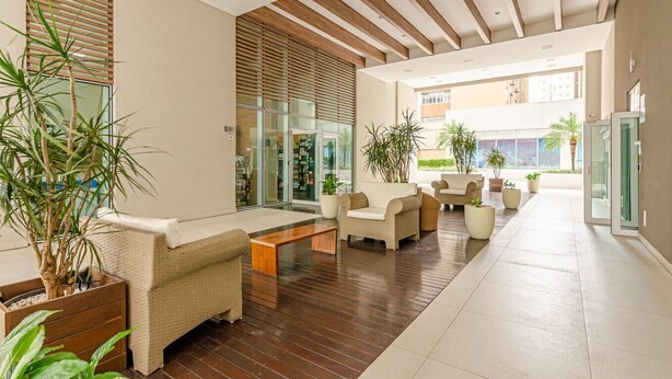 A modern lobby with wicker furniture, a wooden floor, and large windows.