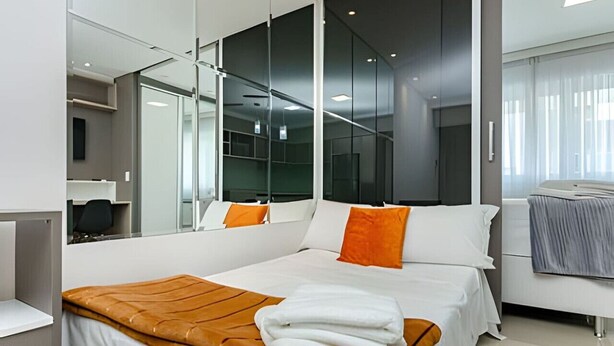 A modern hotel room with a large bed, a mirror, and a bathroom.