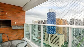 A balcony with a glass railing, a brick wall, and a view of city buildings. - Apartamento com Vista do 22º Andar, Piscina Aquecida e Garagem | Batel, Curitiba (Curitiba)