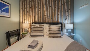 Un letto rifatto con cuscini a righe, una testiera e un comodino con una lampada.