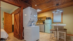 Una cucina compatta con lavatrice, un piccolo tavolo da pranzo con due sedie e mobili in legno.
