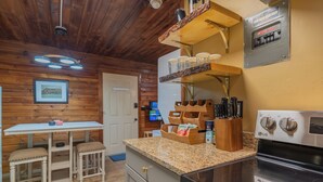 Una cucina con pareti in legno, un piano di lavoro in granito, un fornello e una macchina per il caffè.