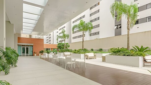 A spacious indoor area with a high ceiling, modern architecture, and a mix of seating areas and greenery.