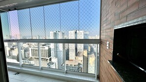 A high-rise building with a view of a cityscape through a window with a metal grid.