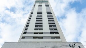 A tall, modern building with a grid of windows and a flat roof. - Studio 25º Andar Sacada e Linda Vista no Hydepark (Curitiba)