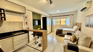 A modern hotel room with a kitchenette, a sofa, a bed, and a TV. - Studio no lifespace Curitiba batel, com garagem (Curitiba)