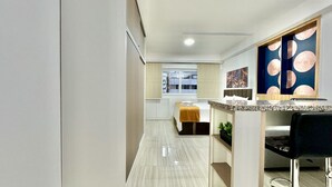 A modern kitchen with a marble countertop, a built-in oven, and a window with a view of the city.