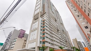 A high-rise building with multiple balconies, a modern architectural design, and a surrounding urban environment.