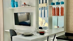 A modern kitchen with a flat-screen TV mounted above a white countertop.
