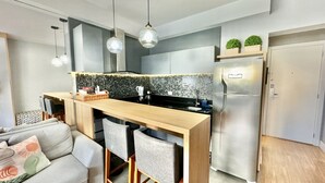 Une cuisine moderne dotée d’un îlot central en bois, d’appareils électroménagers en acier inoxydable, de luminaires suspendus et d’un dosseret de carrelage gris.