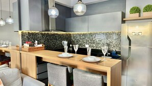 Une cuisine moderne dotée d’un bar en bois, d’un réfrigérateur en acier inoxydable et d’un dosseret en mosaïque.