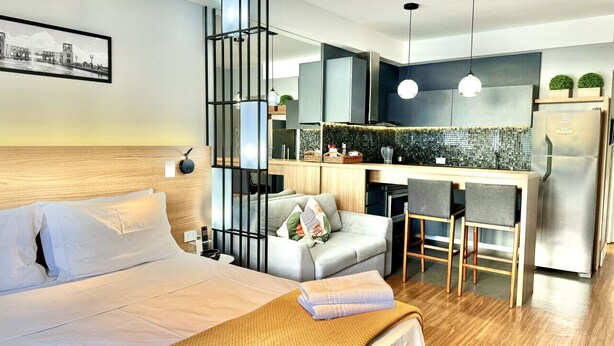 Une chambre d’hôtel moderne équipée d’un lit, d’un canapé, d’un petit coin cuisine et d’une table à manger.