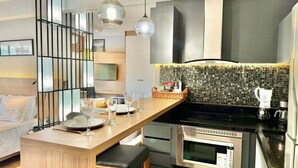 Une cuisine moderne dotée d’un îlot central en bois, d’appareils électroménagers en acier inoxydable et d’un dosseret carrelé.