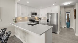 Une cuisine moderne avec des meubles blancs, des appareils en acier inoxydable et un îlot central.