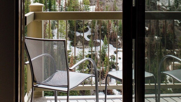 A balcony with metal chairs and a view of a snowy mountain landscape.