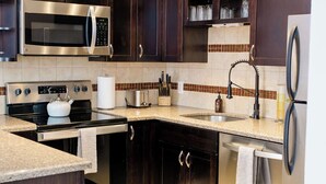 A modern kitchen with dark wooden cabinets, stainless steel appliances, and a tiled backsplash.