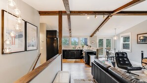 A modern kitchen with dark cabinets, a black refrigerator, and a dining area with a black leather chair. - 30-Day Pet Friendly, BBQ Grill, Walking Distance to Downtown and City Beach! (Whitefish)