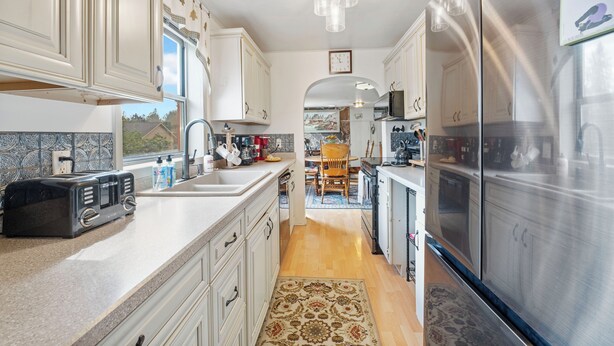 A kitchen with white cabinets, a stainless steel refrigerator, a toaster, and a patterned rug. - 30-Day Min, Walking Distance to Downtown & Lake + Pet Friendly! (Whitefish)
